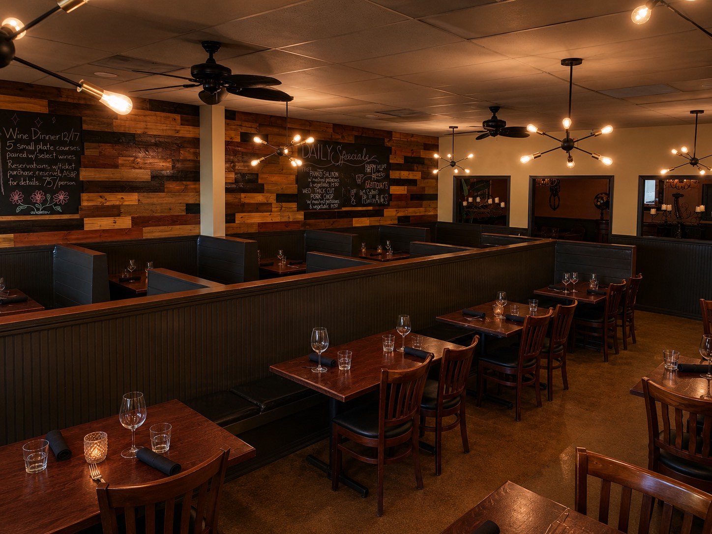 The warm, low-lit dining room at Mean Deans with reclaimed-wood walls, booth seating and candlelit tables