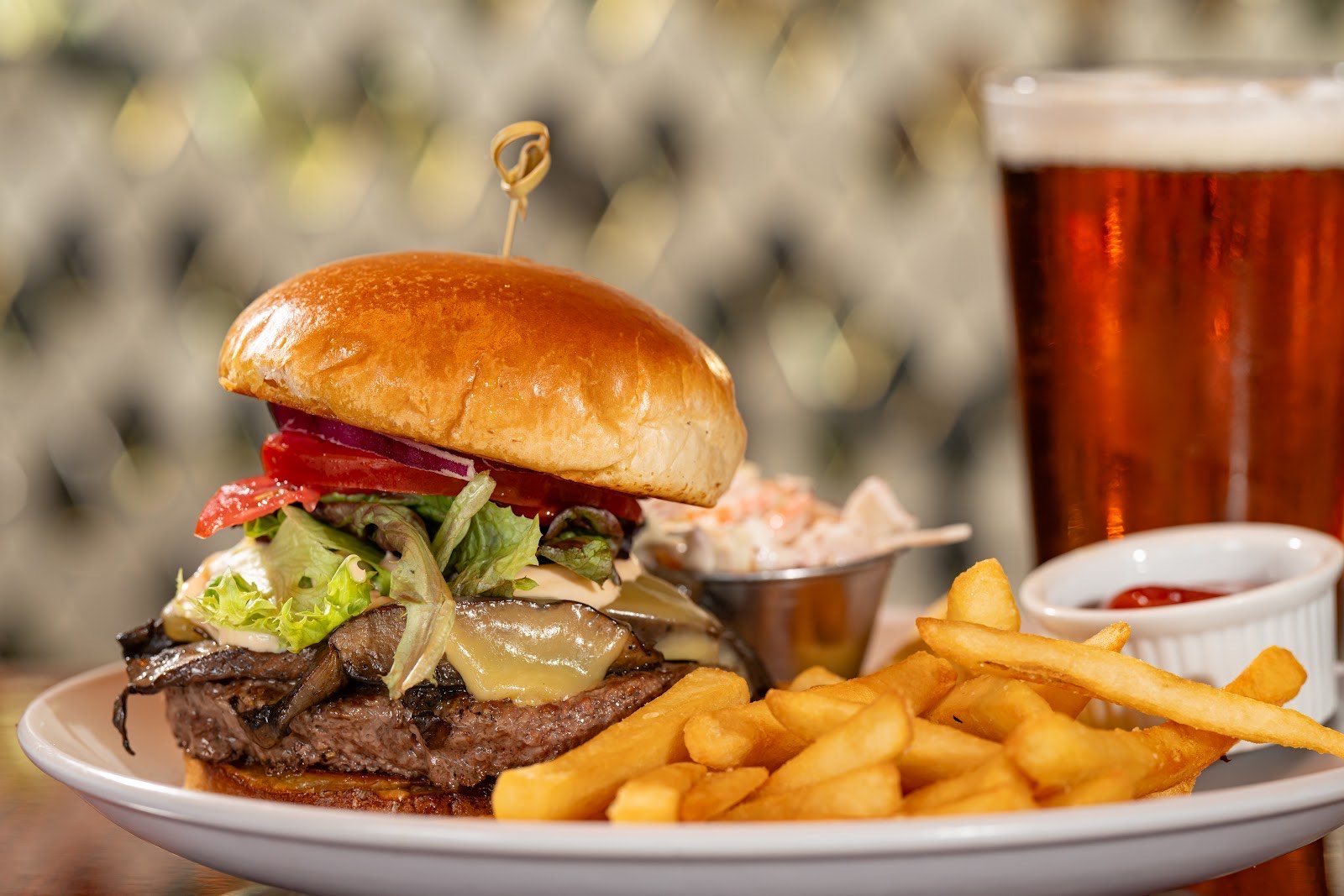 A hand-pressed Mean Deans burger with melted cheese, sautéed mushrooms, fries and a draft beer at the bar